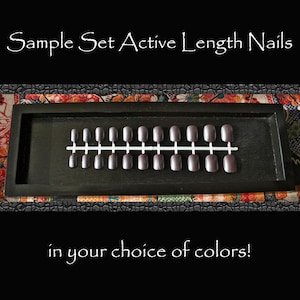 May include: A set of 18 false nails in a black tray. The nails are arranged in rows and are all the same length. The nails are a dark brown color. The text "Sample Set Active Length Nails" is at the top of the image. The text "in your choice of colors!" is at the bottom of the image.