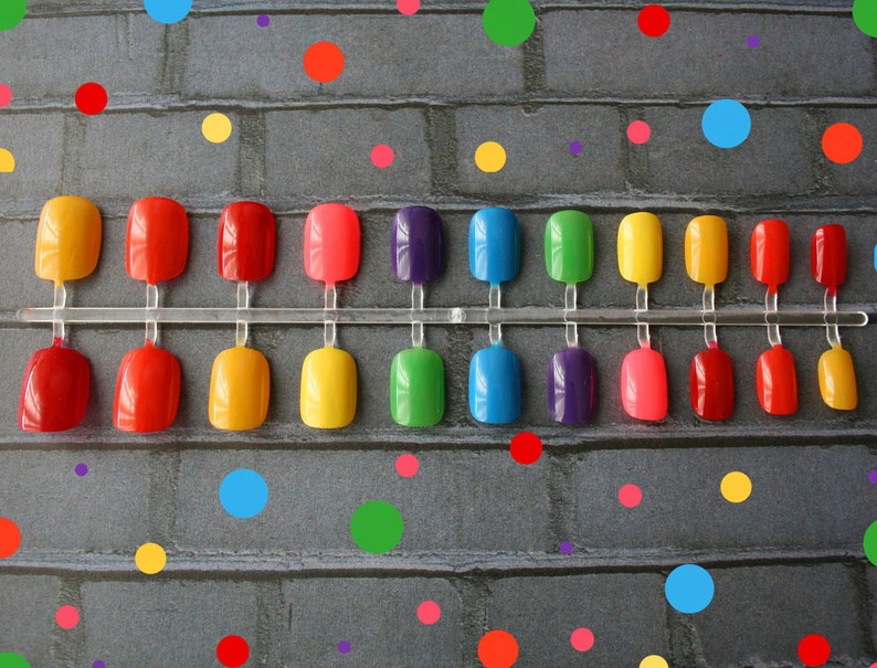 24 short press on nails in rainbow colors- red, orange, yellow, green, blue, indigo and violet. Nails are on a polka-dot background