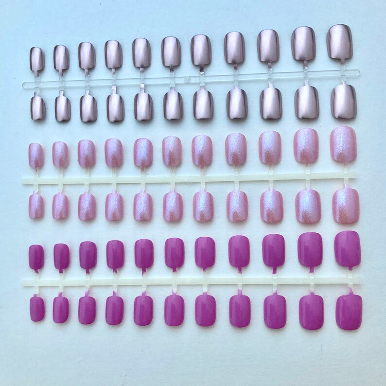 3 sets of short false nails in Metallic pink, iridescent light pink and lilac pink are shown on a white background.