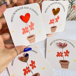 Peut inclure: Trois cartes avec un motif de pot de fleurs et un autocollant en forme de cœur sur chacune. Le texte sur les cartes est "Merci de m'avoir aidé à grandir".