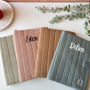 Peut inclure: Quatre housses en tissu matelassées avec des noms personnalisés, Eden, Dilan, et deux housses vierges. Les housses sont dans des tons de vert, marron et rose.