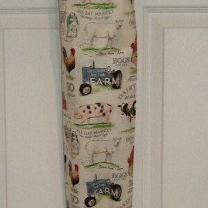 K&ouml;nnte beinhalten: Eine wei&szlig;e Stofftasche mit einem Bauernhof-Motiv. Die Tasche zeigt ein sich wiederholendes Muster aus Schweinen, Schafen, H&uuml;hnern, einem Traktor und den Worten "Go Organic", "All-Day Market", "Eggs for Sale", "On the Farm" und "Dairy Artisan".