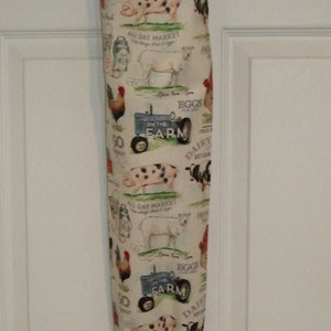 K&ouml;nnte beinhalten: Eine wei&szlig;e Stofftasche mit einem Farm-Motiv. Der Druck zeigt Schweine, K&uuml;he, H&uuml;hner, einen Traktor und den Text "Go Dairy", "All-Day Market", "Eggs for Sale" und "On the Farm".