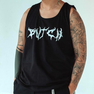 May include: Black tank top with the word "BUTCH" in a white, stylized font. The tank top is worn with black pants and a silver chain. The person has tattoos on their arms.