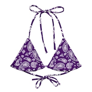May include: A purple halter bikini top with a white paisley pattern. The triangle cups are connected by ties that go around the neck and tie at the back. The bikini top is made of a soft, lightweight fabric.