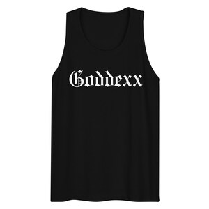 Peut inclure: Débardeur noir avec le mot "Goddexx" imprimé en blanc, en lettres gothiques sur la poitrine. Le débardeur a un col rond et est sans manches.