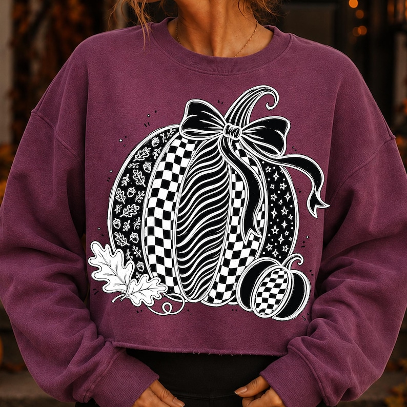 K&ouml;nnte beinhalten: Ein dunkelweinrotes Langarm-Sweatshirt mit einer gro&szlig;en Grafik von zwei K&uuml;rbissen. Der Hauptk&uuml;rbis hat Abschnitte mit Karomustern, Wellenlinien und Bl&auml;ttern, gekr&ouml;nt von einer schwarzen Schleife. Ein kleinerer karierter K&uuml;rbis steht daneben.