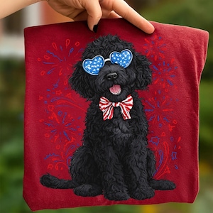 Pu&ograve; includere: Un asciugamano rosso con un cane nero che indossa occhiali da sole a forma di cuore con un motivo a stelle blu e un papillon rosso, bianco e blu. Lo sfondo presenta un disegno di fuochi d'artificio in rosso e blu.