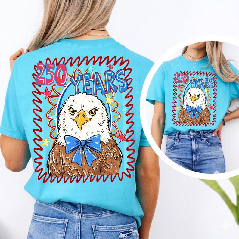 Pu&ograve; includere: Una maglietta azzurra con una grafica di un'aquila con un papillon blu e la scritta "250 YEARS". Il disegno &egrave; incorniciato da un bordo rosso e blu con stelle. La maglietta &egrave; a girocollo e maniche corte.