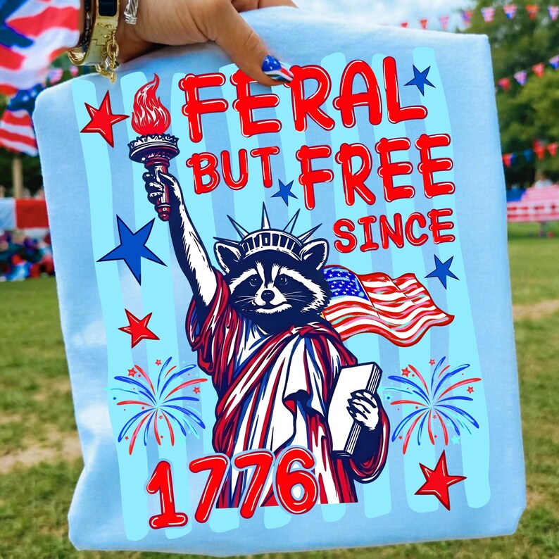 Feral But Free retro raccoon 4th of July sublimation design on a heather gray t-shirt.
