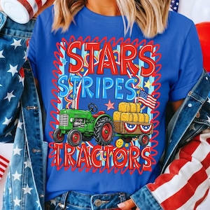 Pode incluir: Camiseta azul com um gr&aacute;fico com um trator verde puxando uma carro&ccedil;a de fardos de feno, uma bandeira americana e as palavras "STARS STRIPES TRACTORS" em vermelho e azul. O design tem um tema patri&oacute;tico.