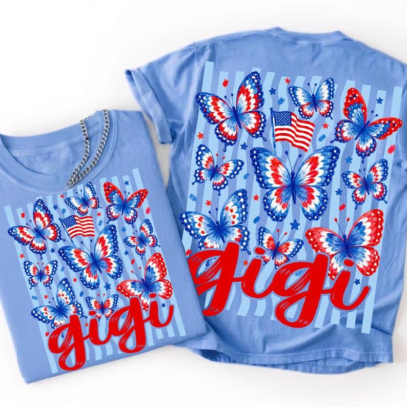 May include: A light blue t-shirt featuring a graphic print of red, white, and blue butterflies, American flags, and small stars over vertical light blue stripes. The word "gigi" is printed in a large, bold, red script font across the bottom.