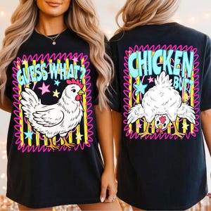 May include: Black t-shirt with a whimsical chicken graphic. The front features a white chicken with the text "GUESS WHAT?" and stars. The back displays a chicken's rear with the words "CHICKEN BUTT".