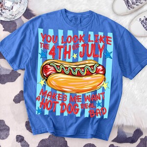 May include: A blue t-shirt with a graphic of a hot dog and the text "You look like the 4th of July makes me want a hot dog real bad." The design features a hot dog with mustard and a bun.