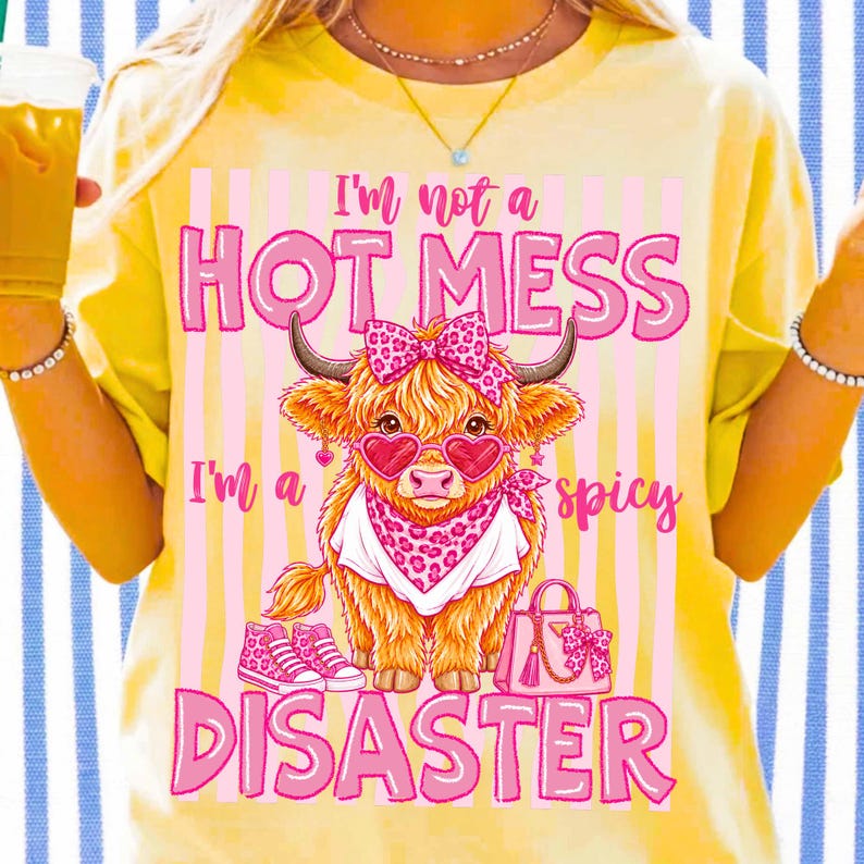 K&ouml;nnte beinhalten: Gelbes T-Shirt mit einer Grafik einer Highland-Kuh mit herzf&ouml;rmiger Sonnenbrille, Schleife und Bandana. Der Text lautet: &bdquo;I'm not a HOT MESS, I'm a spicy DISASTER.&ldquo;