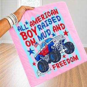 K&ouml;nnte beinhalten: Rosa Decke mit dem Text "ALL AMERICAN BOY RAISED ON MUD AND FREEDOM" und einer Grafik eines rot, wei&szlig; und blau gef&auml;rbten Monster Trucks. Die Decke hat blaue und rosa Streifen und Sterne.