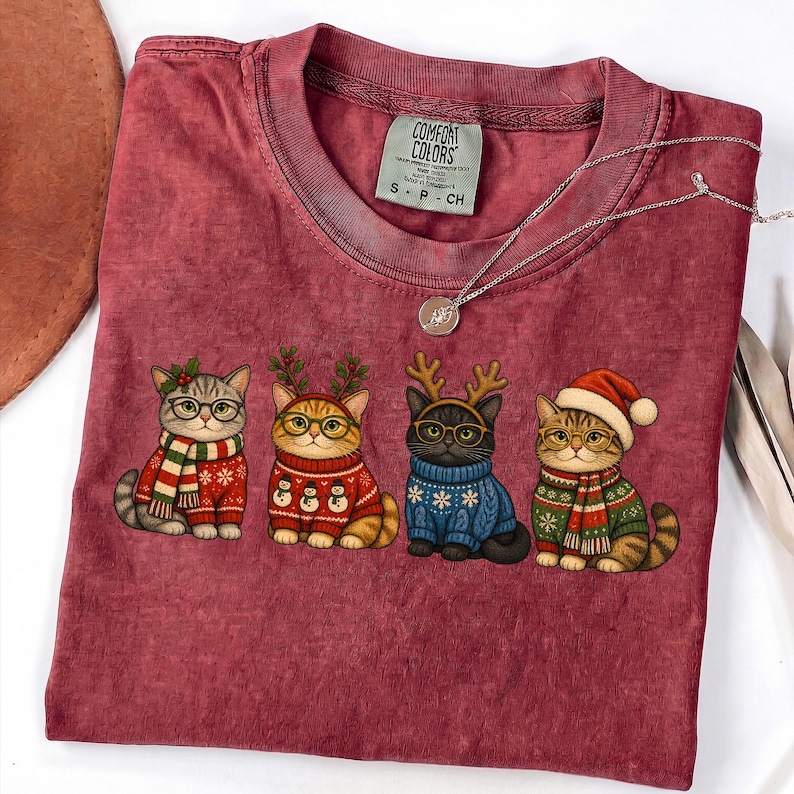Four adorable Christmas cats wearing festive sweaters and holiday accessories PNG design