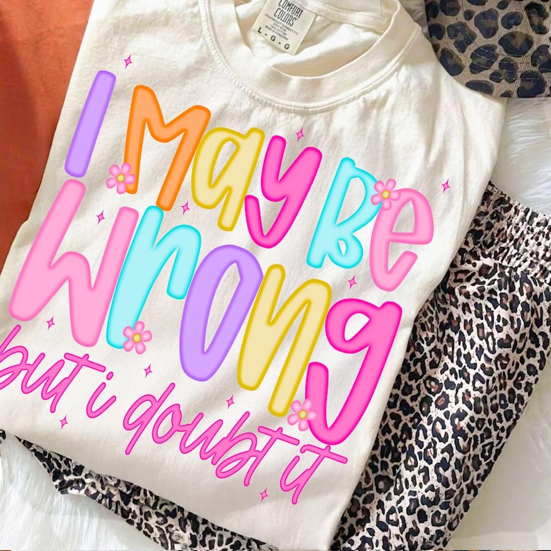 Op de afbeelding: Cr&egrave;mekleurig T-shirt met de tekst "I MAY BE WRONG but i doubt it" in kleurrijke letters. Het shirt wordt gecombineerd met een broek met luipaardprint. Het shirt heeft een Comfort Colors label.