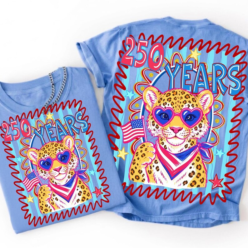 Op de afbeelding: Twee lichtblauwe t-shirts met een luipaard met een hartvormige zonnebril en een Amerikaanse vlag. De shirts hebben de tekst "250 YEARS" in een rood-blauw ontwerp.