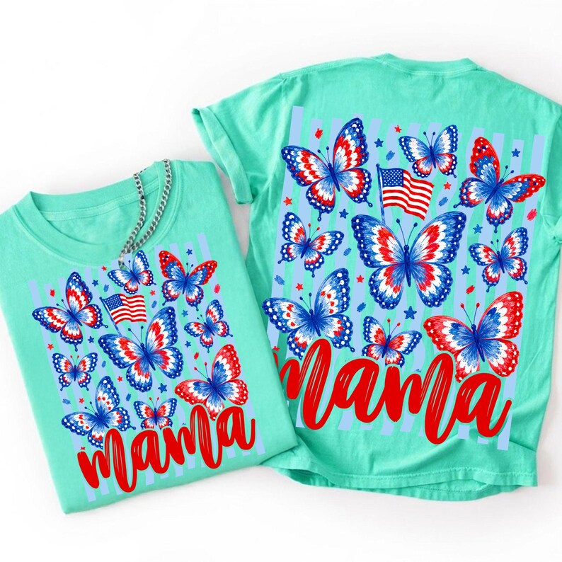 May include: A light green t-shirt featuring a graphic print of red, white, and blue butterflies, small stars, and an American flag. The word mama is written in a bold red script font across the bottom of the design. The shirt has a crew neckline.