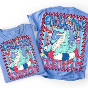 Puede incluir: Dos camisetas azul claro con un gr&aacute;fico de un caim&aacute;n con gafas de sol flotando en una boya roja, blanca y azul. El texto "Chill the Fourth Out" est&aacute; impreso en las camisetas en rojo y azul.