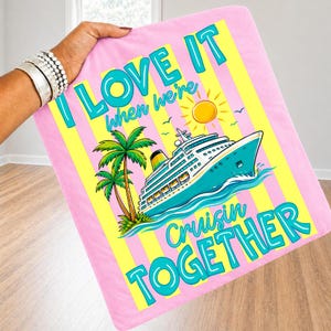 May include: Pink blanket with yellow stripes and the text "I LOVE IT when we're Cruisin TOGETHER." Features a cruise ship, palm trees, and a sun graphic. The blanket is held by a person.