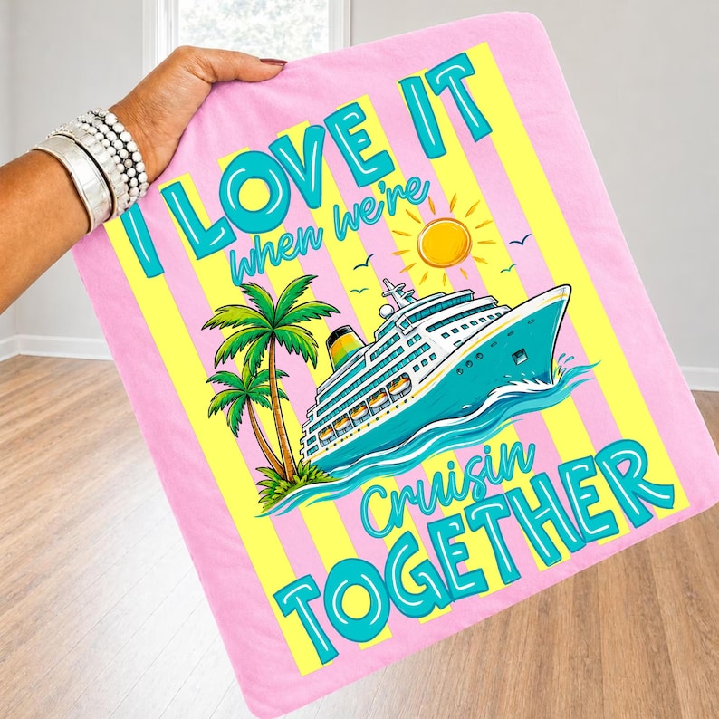May include: Pink blanket with yellow stripes and the text "I LOVE IT when we're Cruisin TOGETHER." Features a cruise ship, palm trees, and a sun graphic. The blanket is held by a person.