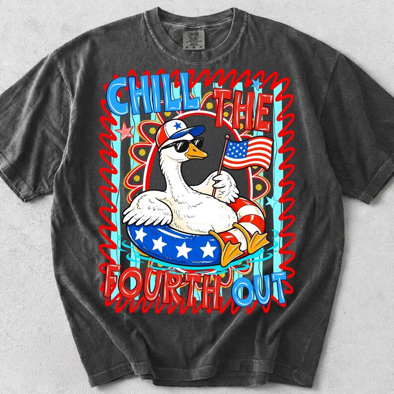 Peut inclure: T-shirt gris fonc&eacute; avec un dessin d'oie de dessin anim&eacute; portant des lunettes de soleil et un chapeau patriotique, tenant un petit drapeau am&eacute;ricain. Le t-shirt porte les mots "Chill the Fourth Out" en rouge et bleu, avec un design festif.