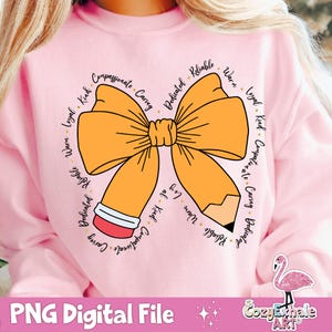 May include: A pink sweatshirt featuring a yellow bow and a pencil design. The bow and pencil are encircled by words describing positive character traits, such as "compassionate", "caring", "dedicated", "reliable", "warm", "loyal", and "kind".
