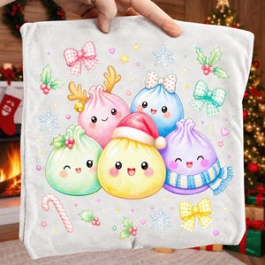 May include: A light grey fabric square featuring a colourful graphic print of five smiling, round dumpling characters. The characters are decorated with festive elements including a Santa hat, a blue striped scarf, reindeer antlers, and bows.
