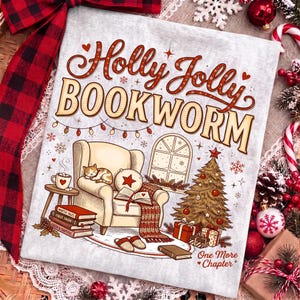 Op de afbeelding: Een lichtgrijs stoffen vierkant met de tekst Holly Jolly BOOKWORM en One More Chapter. De illustratie toont een gezellige fauteuil met een slapende kat, een stapel boeken, een kerstboom met cadeautjes en een raam met kerstverlichting.