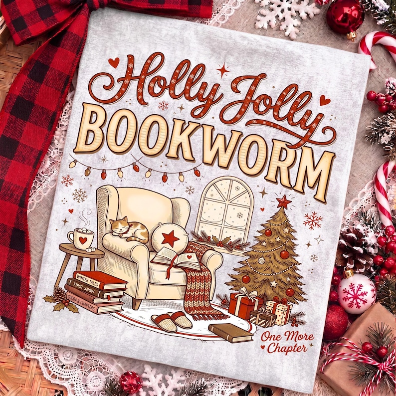 Op de afbeelding: Een lichtgrijs stoffen vierkant met de tekst Holly Jolly BOOKWORM en One More Chapter. De illustratie toont een gezellige fauteuil met een slapende kat, een stapel boeken, een kerstboom met cadeautjes en een raam met kerstverlichting.