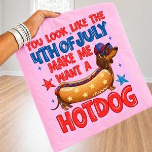 May include: Pink blanket with the text "You look like the 4th of July make me want a hotdog." Features a cartoon dachshund wearing sunglasses and a hat, designed as a hotdog. Red, blue, and white colors.