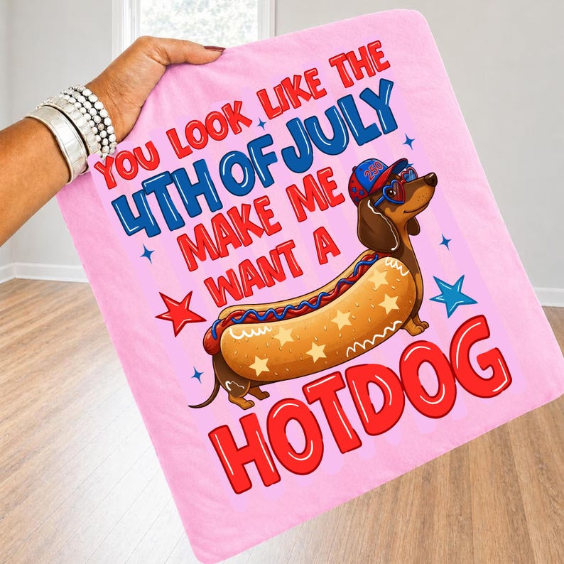 May include: Pink blanket with the text "You look like the 4th of July make me want a hotdog." Features a cartoon dachshund wearing sunglasses and a hat, designed as a hotdog. Red, blue, and white colors.