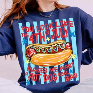 May include: Navy blue sweatshirt with a graphic of a hot dog and the text "You look like the 4th of July makes me want a hot dog real bad." The design includes red, yellow, and blue colors. The sweatshirt has a crew neck.