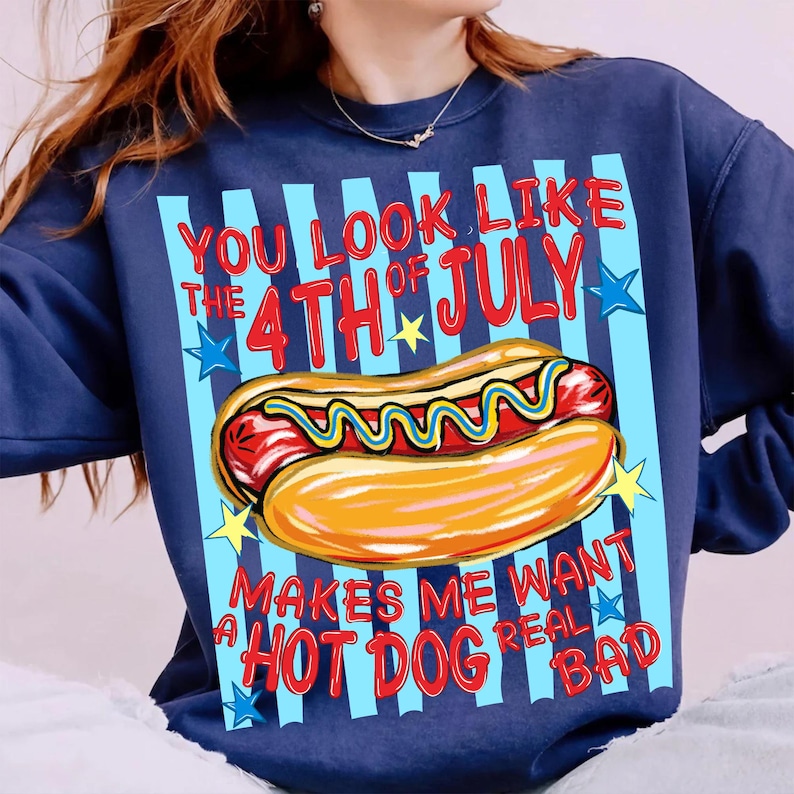 May include: Navy blue sweatshirt with a graphic of a hot dog and the text "You look like the 4th of July makes me want a hot dog real bad." The design includes red, yellow, and blue colors. The sweatshirt has a crew neck.