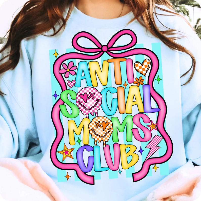 K&ouml;nnte beinhalten: Hellblaues Sweatshirt mit einem farbenfrohen Aufdruck &bdquo;ANTI SOCIAL MOMS CLUB&ldquo;. Das Design umfasst Smileys, Herzen, Blumen und einen Blitz, alles schwarz umrandet und auf einem rosa Band platziert.