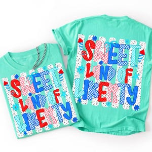 May include: Two mint green t-shirts featuring a graphic print with the text SWEET LAND OF LIBERTY in red, white, and blue checkered and polka dot patterns. The design includes small firework and star illustrations over vertical black dots.