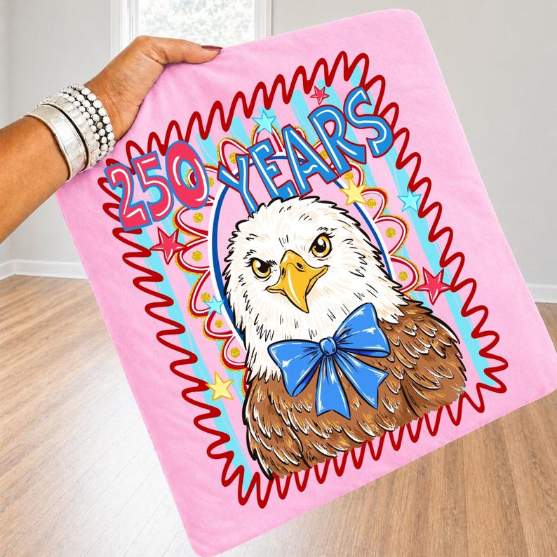 Pu&ograve; includere: Coperta rosa con un'aquila dei cartoni animati con un papillon blu e la scritta "250 YEARS". L'aquila &egrave; incorniciata da un bordo ondulato rosso e stelle. La coperta &egrave; tenuta da una persona.