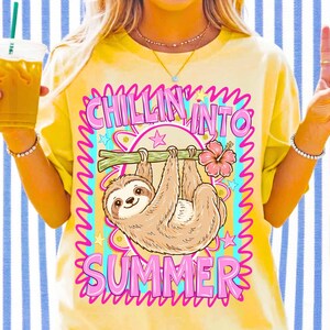 Może przedstawiać: Ż&oacute;łta koszulka z grafiką leniwca wiszącego na gałęzi, z r&oacute;żowym napisem "Chillin' Into Summer". Projekt zawiera r&oacute;żowy kwiat hibiskusa i gwiazdy. Letni motyw.