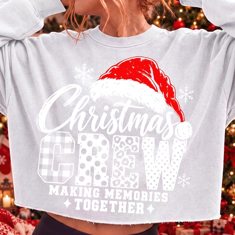 May include: A light gray long-sleeve sweatshirt featuring a red Santa hat graphic above the white text Christmas CREW. The letters in CREW have varied patterns including plaid, polka dots, and leopard print. Below is the text MAKING MEMORIES TOGETHER.