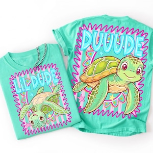 May include: Two turquoise t-shirts featuring turtle designs. One shirt displays "Lil Dude" and the other "Duuude" in a wavy font. The turtle illustrations are green and tan, with pink and yellow accents.