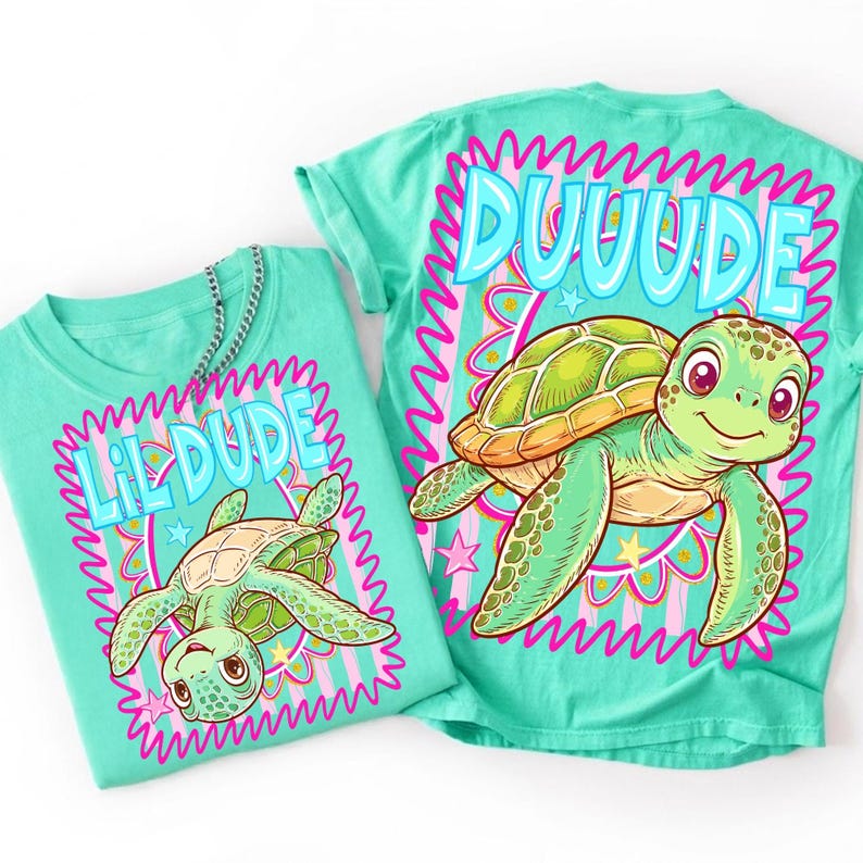 May include: Two turquoise t-shirts featuring turtle designs. One shirt displays "Lil Dude" and the other "Duuude" in a wavy font. The turtle illustrations are green and tan, with pink and yellow accents.
