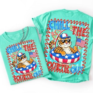 以下が含まれることがあります： 2枚の明るいティール色のTシャツ。7月4日のテーマです。各シャツには、サングラスと愛国的な帽子をかぶった漫画のトラが描かれており、赤、白、青の浮き輪に浮かび、アメリカ国旗を持っています。「Chill the Fourth Out」というテキストが表示されています。