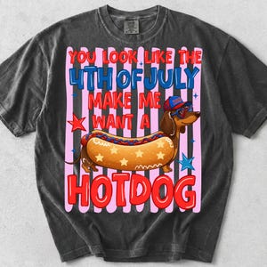 May include: Dark gray t-shirt with a graphic of a dachshund dressed as a hot dog, wearing sunglasses and a hat. Text reads "You look like the 4th of July, make me want a hotdog."