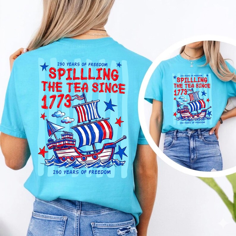 Pu&ograve; includere: T-shirt azzurra con una grafica raffigurante una nave e la scritta "Spilling the Tea Since 1773" in rosso e bianco. Il design include stelle e la frase "250 Years of Freedom".