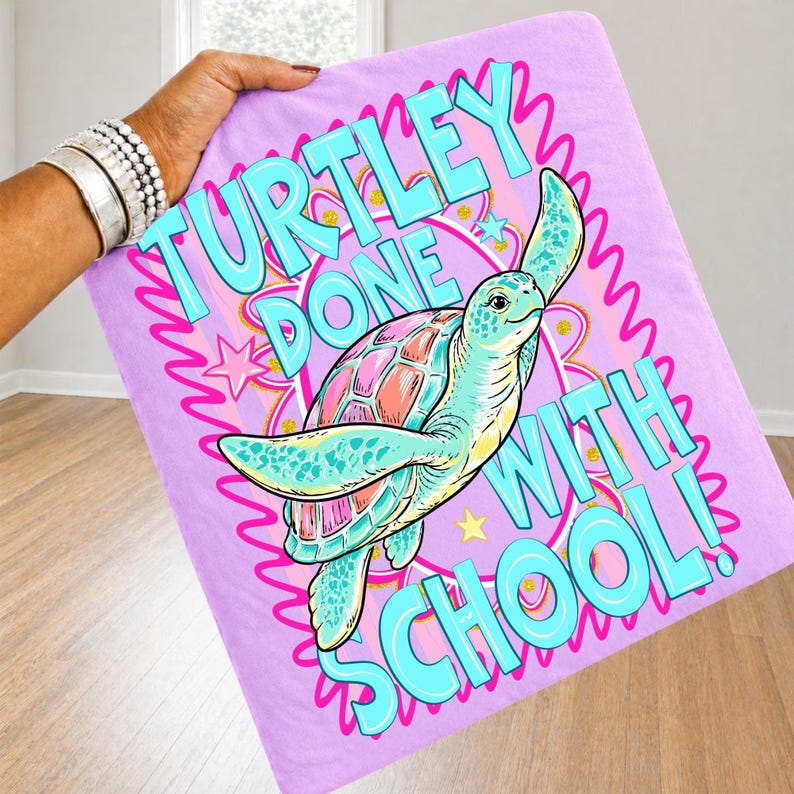 以下が含まれることがあります： ターコイズとピンクで「TURTLEY DONE WITH SCHOOL！」と書かれたライラックのビーチタオル。ピンクの甲羅とターコイズの体を持つ漫画のウミガメがデザインされています。