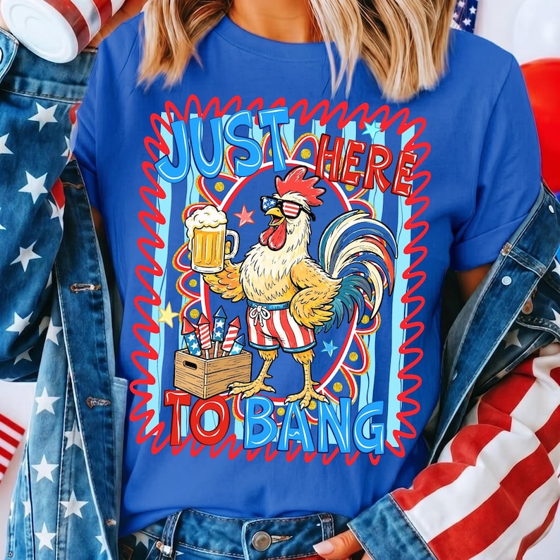 May include: Blue t-shirt with a rooster graphic wearing sunglasses and holding a beer mug. The text on the shirt reads "JUST HERE TO BANG" in red and blue. The rooster is wearing red, white, and blue shorts. The shirt is part of a patriotic theme.