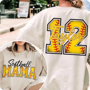 Puede incluir: Una sudadera blanca con un diseño de softball en la espalda. El diseño presenta una pelota de softball amarilla con costuras rojas y el número 12 con el nombre Taylor escrito en su interior. La parte delantera de la sudadera tiene el texto "Softball Mama" con un diseño de pelota de softball amarilla.