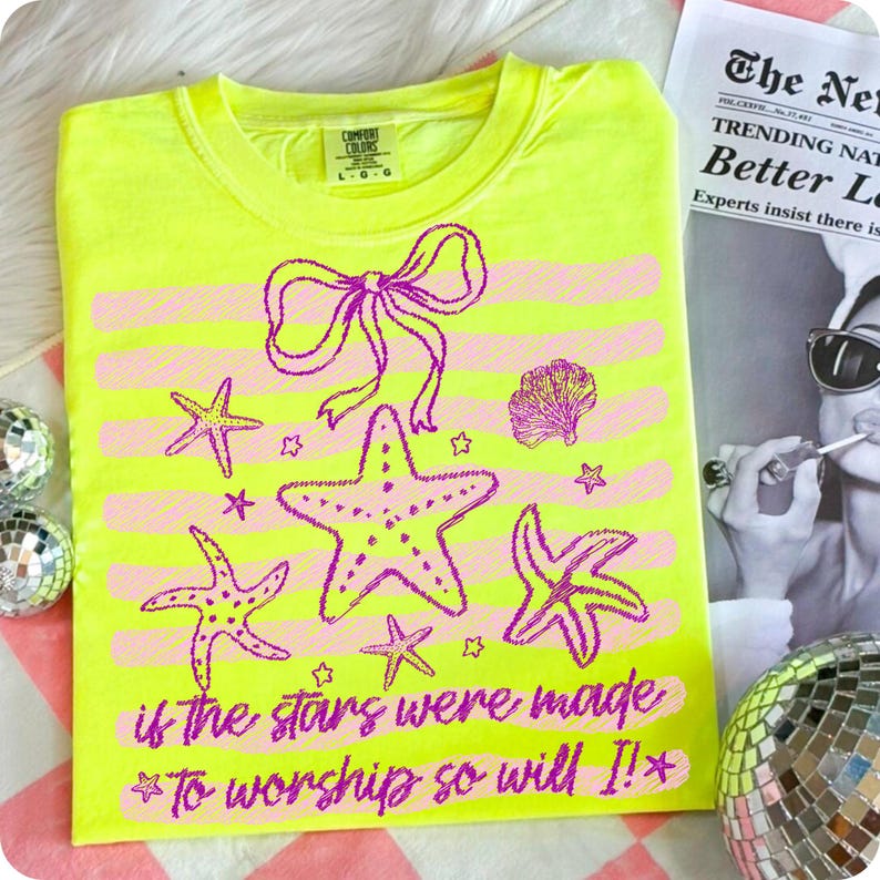 Op de afbeelding: Neon geel t-shirt met een roze strik, zeesterren en schelpmotief. De tekst "if the stars were made to worship so will I!" is roze gedrukt. Het shirt is van het merk Comfort Colors, maat L-G.